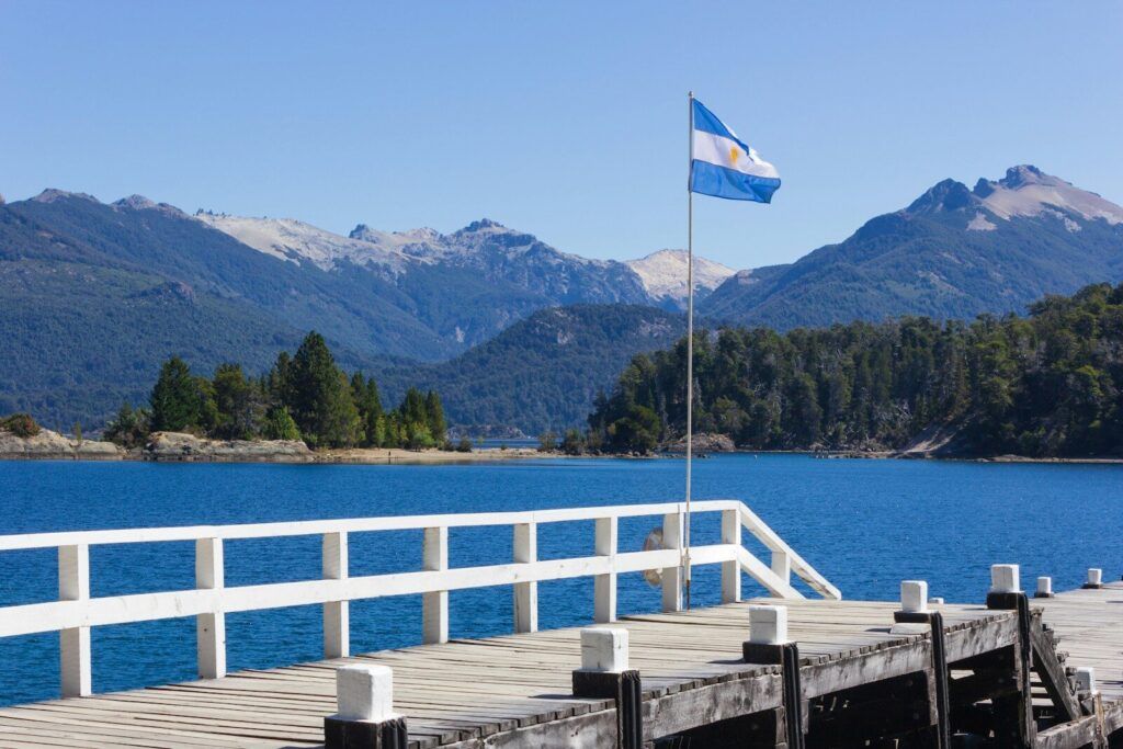 Photo by Fernando Távora white and blue flag on wooden dock near body of water during daytime
