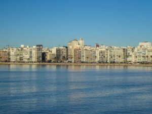 A serene view of Montevideo's skyline reflecting on the waterfront under a clear blue sky.