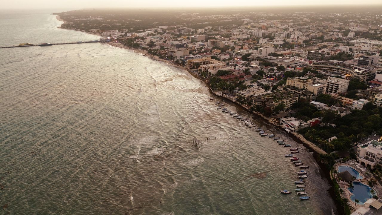 Stunning aerial view of Playa del Carmen coastline at dusk with cityscape and beachfront.