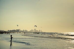 A vibrant sunset beachscape in Cartagena with kite surfers and skyline in the background.